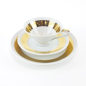 May include: A white teacup and saucer set with gold trim. The cup and saucer have a delicate floral pattern in gold.