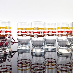 Peut inclure: Ensemble de six verres à boire en verre transparent avec un motif géométrique rouge, jaune et marron.