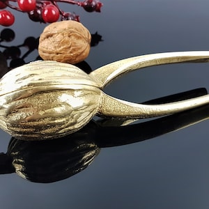 以下が含まれることがあります： クルミの形をした金色の金属製のナッツクラッカー。ナッツクラッカーは、ナッツを割るために開閉するヒンジ付きの顎を持っています。
