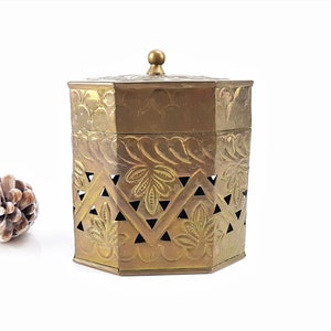 Peut inclure: Boîte octogonale en laiton avec un couvercle et des motifs floraux complexes. La boîte présente un motif découpé décoratif et une finition lisse et polie.