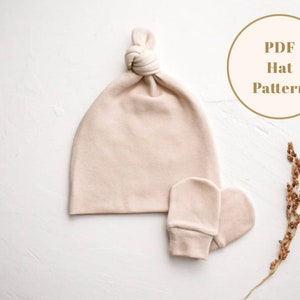 Puede incluir: Un patr&oacute;n PDF para un gorro de punto beige con nudo y mitones a juego. El patr&oacute;n est&aacute; disponible para descargar.