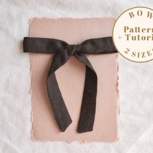 Op de afbeelding: Een bruine strik van stof met een eenvoudig ontwerp. De strik ligt op een lichtroze vel papier met de tekst "BOW Pattern + Tutorial 2 SIZES" in een cirkel.
