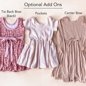 Pode incluir: Tr&ecirc;s vestidos para meninas com diferentes op&ccedil;&otilde;es de adi&ccedil;&atilde;o. O vestido &agrave; esquerda tem um la&ccedil;o de gravata nas costas, o vestido do meio tem bolsos e o vestido &agrave; direita tem um la&ccedil;o no centro.