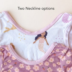 Pode incluir: Duas camisas sem mangas com decotes diferentes. A camisa de cima tem um decote em U e uma estampa de sereia em tons de rosa e dourado. A camisa de baixo tem um decote redondo e uma estampa floral em tons de rosa e roxo. O texto "Two Neckline options" &eacute; vis&iacute;vel na parte superior da imagem.
