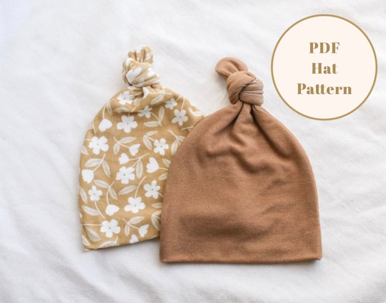 Puede incluir: Dos gorros de punto, uno con estampado floral y otro marr&oacute;n liso. Ambos gorros tienen un nudo en la parte superior. El texto "PDF Hat Pattern" es visible en la imagen.