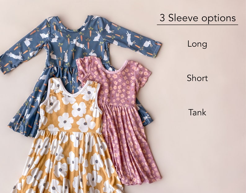 Pode incluir: Tr&ecirc;s vestidos para meninas com diferentes comprimentos de manga: manga comprida, manga curta e sem mangas. O vestido de manga comprida tem um fundo azul com coelhos brancos e cenouras. O vestido de manga curta tem um fundo rosa com flores brancas. O vestido sem mangas tem um fundo amarelo com flores brancas. O texto "3 Sleeve options" est&aacute; no topo da imagem, com "Long", "Short" e "Tank" listados abaixo.