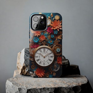 May include: A blue and gold iPhone case with a floral design and a clock face. The clock face has Roman numerals and the words "Gluck Uhr Werk" on it.