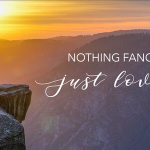 Peut inclure: Un couple en tenue de mariage se tient sur une falaise surplombant une vall&eacute;e au coucher du soleil. Le ciel est d'un orange et d'un jaune vifs, et les montagnes au loin sont silhouett&eacute;es contre le ciel. Le texte "NOTHING FANCY just love" est superpos&eacute; &agrave; l'image.