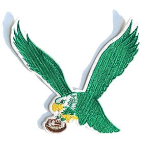 May include: Green embroidered patch of a flying eagle with a football in its talons. The eagle has white feathers on its head and yellow accents on its beak and feet.