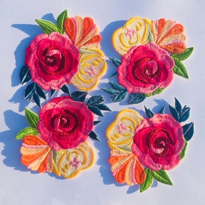 May include: Four embroidered iron-on patches featuring colorful floral designs with pink, red, yellow, and orange flowers. The patches are perfect for adding a touch of whimsy to clothing, bags, or other fabric items.