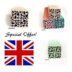 Könnte beinhalten: Drei Holzblöcke mit Leopardenmuster. Die Blöcke sind in Rosa, Blau und Grün. Die Blöcke sind übereinander gestapelt. Der Text "Sonderangebot!" ist in schwarzen Buchstaben auf weißem Hintergrund geschrieben. Im Hintergrund ist eine Union Jack Flagge zu sehen.