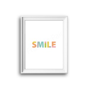 Op de afbeelding: Een wit ingelijst print met het woord "SMILE" in kleurrijke blokletters. Elke letter is gemaakt van verschillende gekleurde rechthoeken.