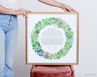 May include: A framed watercolor ketubah with a succulent wreath design. The ketubah is a Jewish marriage contract and features the names "Melanie & Jonathan". The frame is 22 inches by 22 inches.