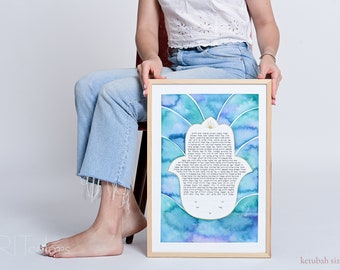 May include: A framed watercolor ketubah with a hamsa design in shades of blue and green. The ketubah is in Hebrew and features a gold star of David. The ketubah is 13 inches by 19 inches.