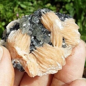 May include: A cluster of light orange and gray crystals. The crystals are arranged in a cluster and have a rough, natural texture.