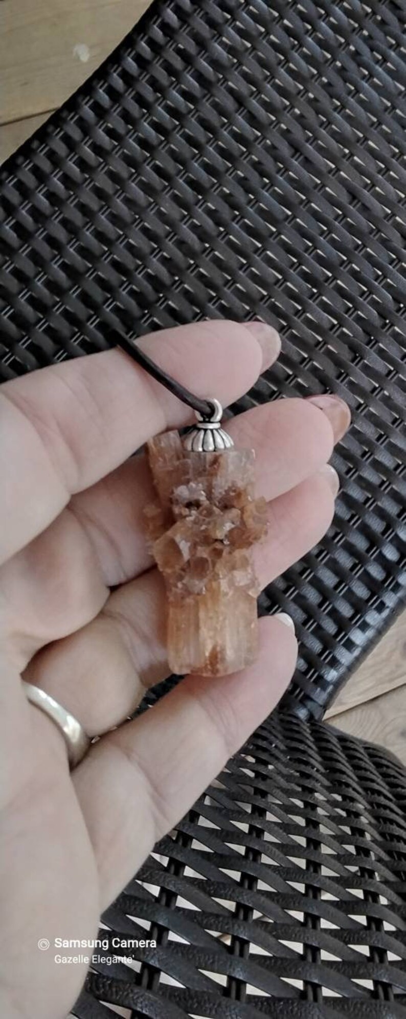 May include: A brown crystal pendant with a silver bail. The crystal is a cluster of small crystals that are translucent and have a slight orange hue.