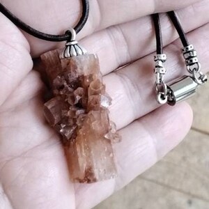 May include: A brown leather cord necklace with a silver clasp and a pendant made of a cluster of brown crystals.