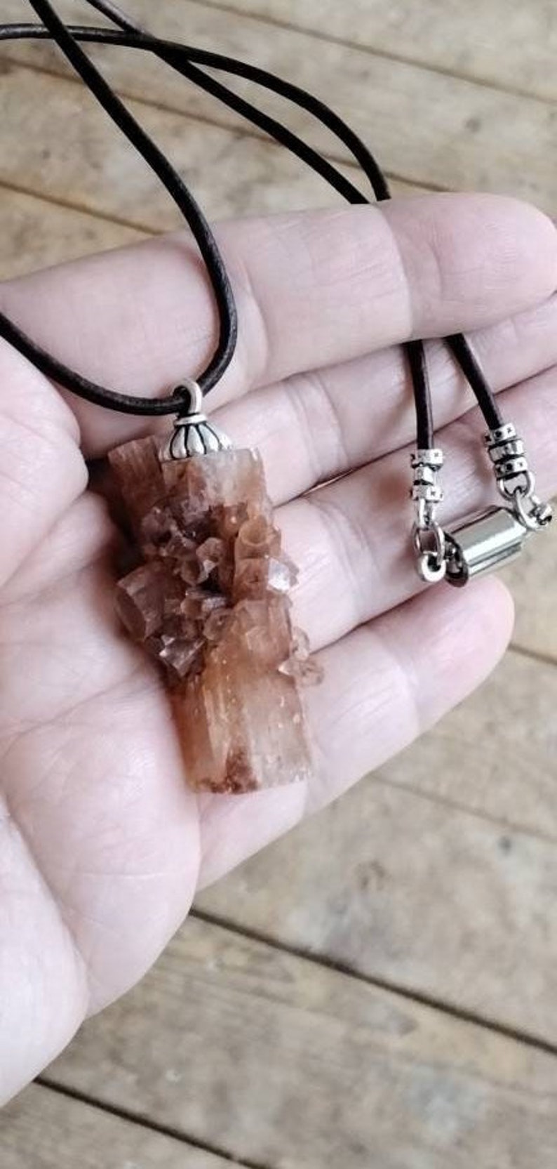 May include: A brown leather cord necklace with a silver clasp and a pendant made of a cluster of brown crystals.