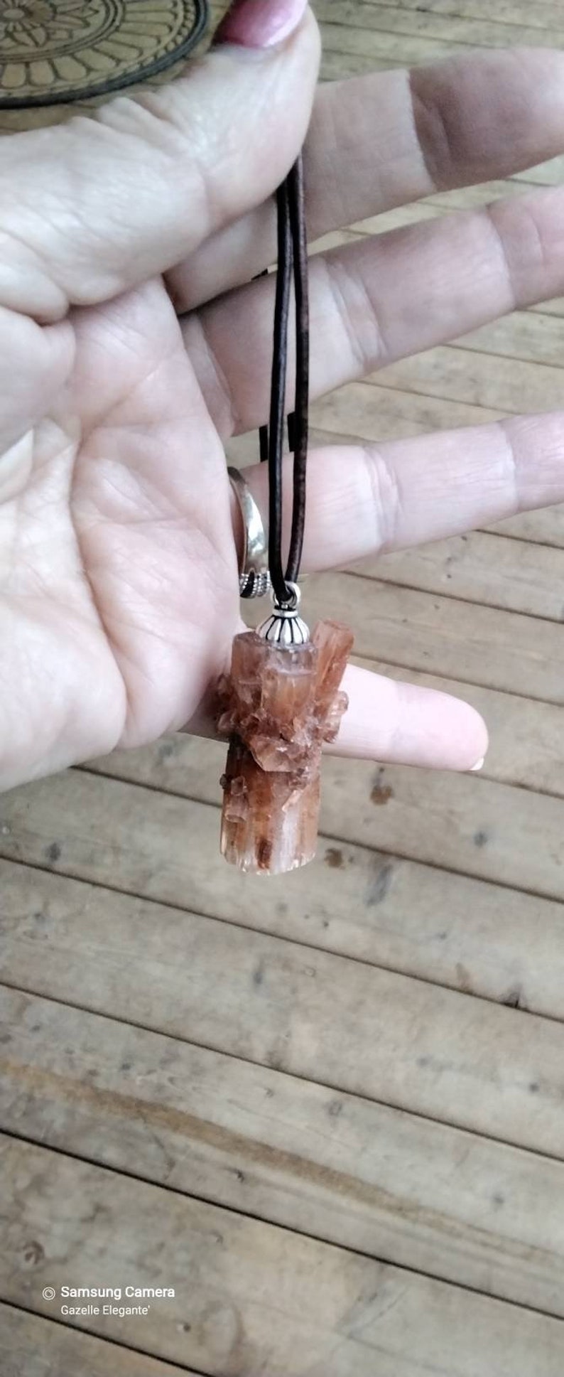 May include: A brown leather cord necklace with a brown crystal pendant. The crystal is a cluster of small crystals.