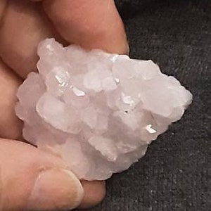 May include: A cluster of small, pale pink crystals. The crystals are clustered together in a rough, natural formation.