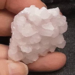 May include: A cluster of pink selenite crystals, a type of gypsum, with a rough, textured surface.