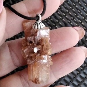 May include: A brown crystal pendant with a silver bail. The crystal is a cluster of small, faceted crystals.