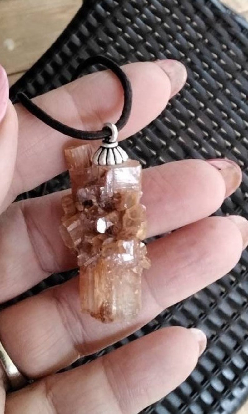 May include: A brown crystal pendant with a silver bail. The crystal is a cluster of small, faceted crystals.