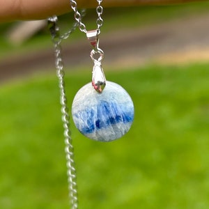 May include: A silver chain necklace with a round blue and white gemstone pendant.