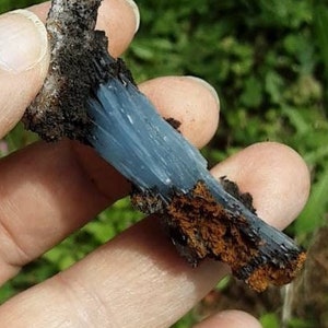 May include: A blue and brown crystal cluster with a rough, natural texture. The crystal is a light blue color and has a fibrous appearance. The brown portion of the crystal is a darker brown and has a more granular texture.