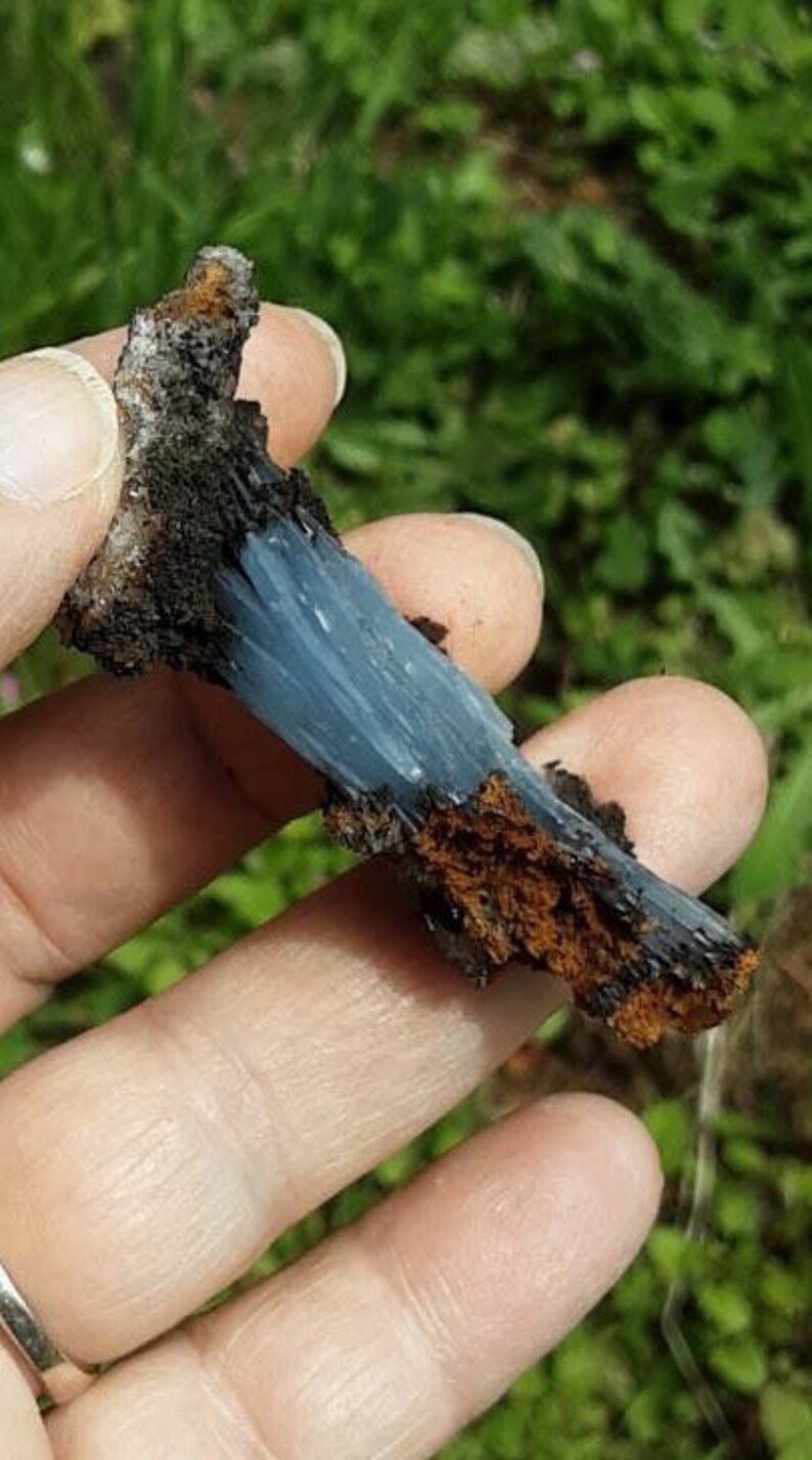 May include: A blue and brown crystal cluster with a rough, natural texture. The crystal is a light blue color and has a fibrous appearance. The brown portion of the crystal is a darker brown and has a more granular texture.