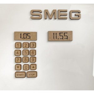 May include: A wooden cutout of a Smeg appliance with a digital display showing 11.55. The appliance has a keypad with numbers 1-9, 0, a start button, and a stop button. The display above the keypad shows 1.05.