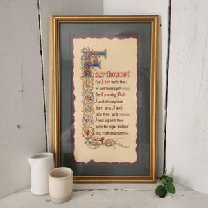 May include: A framed calligraphic print featuring the text Fear thou not for I am with thee: be not dismayed: for I am thy God: I will strengthen thee: yea, I will help thee: yea, I will uphold thee with the right hand of my righteousness.