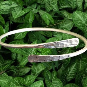 Pode incluir: Um bracelete de prata martelado com um design simples e elegante. O bracelete é aberto e ajustável para se adaptar à maioria dos pulsos.