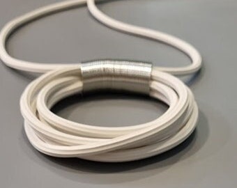 Puede incluir: Collar de cerámica blanca con un diseño de cuerda trenzada y un acento de metal plateado.