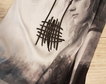 May include: A white dress with a black and white graphic print of a woman's face. The dress has a black lattice design necklace.