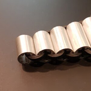 May include: A silver metal bracelet with a series of connected, rounded, interlocking pieces.