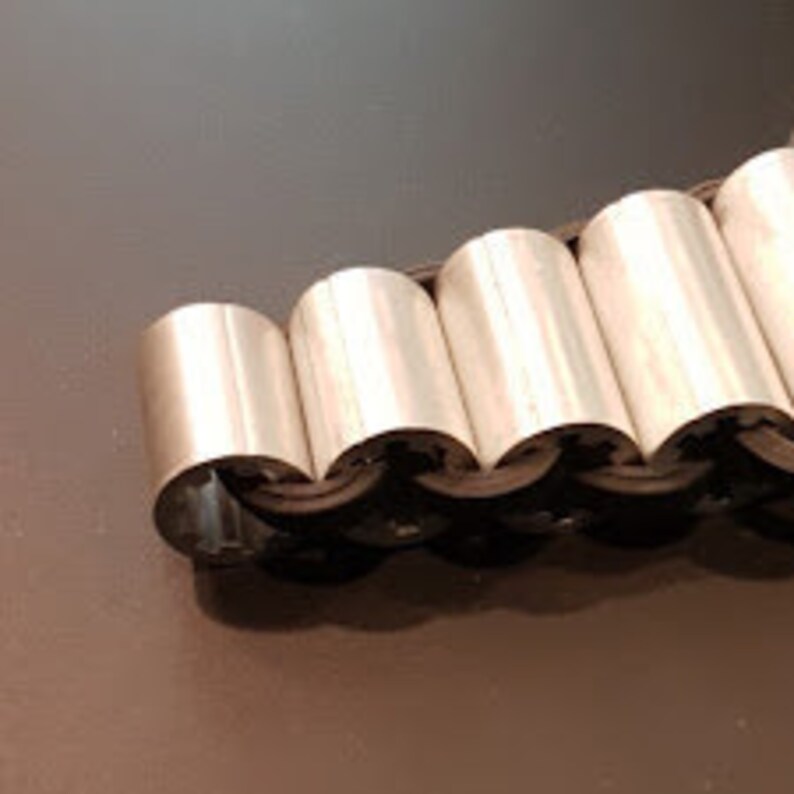 May include: A silver metal bracelet with a series of connected, rounded, interlocking pieces.