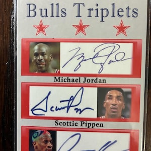 May include: A collectible card featuring the Chicago Bulls "Triplets" with images of Michael Jordan, Scottie Pippen, and Dennis Rodman, each with their signatures. The card has a red border and is encased in a protective sleeve.