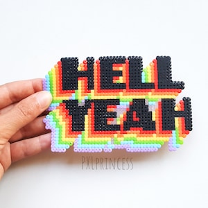 May include: A rainbow-colored pixel art design of the phrase "Hell Yeah" made with small plastic beads.