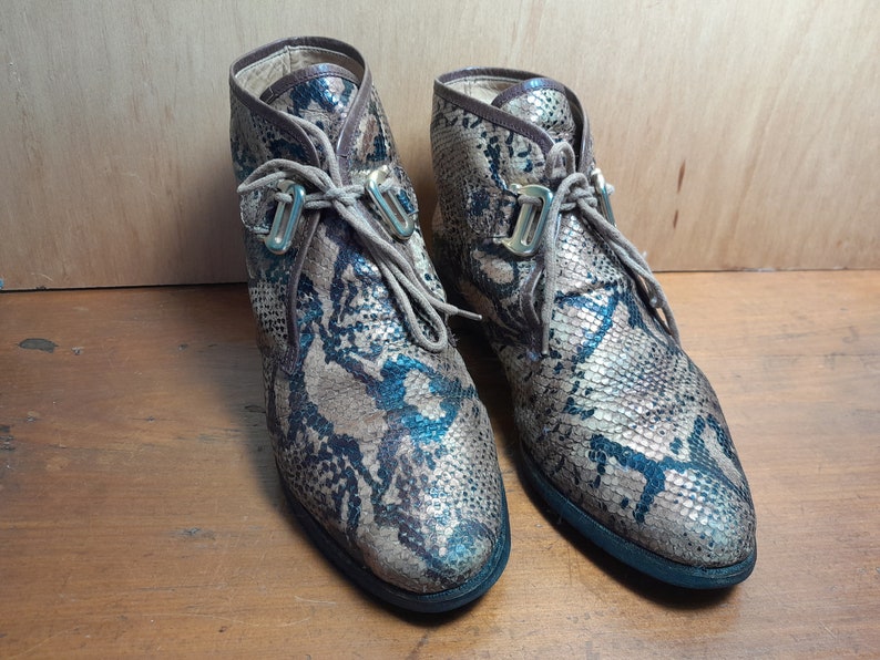 May include: A pair of brown and blue snakeskin ankle boots with gold buckles and laces.