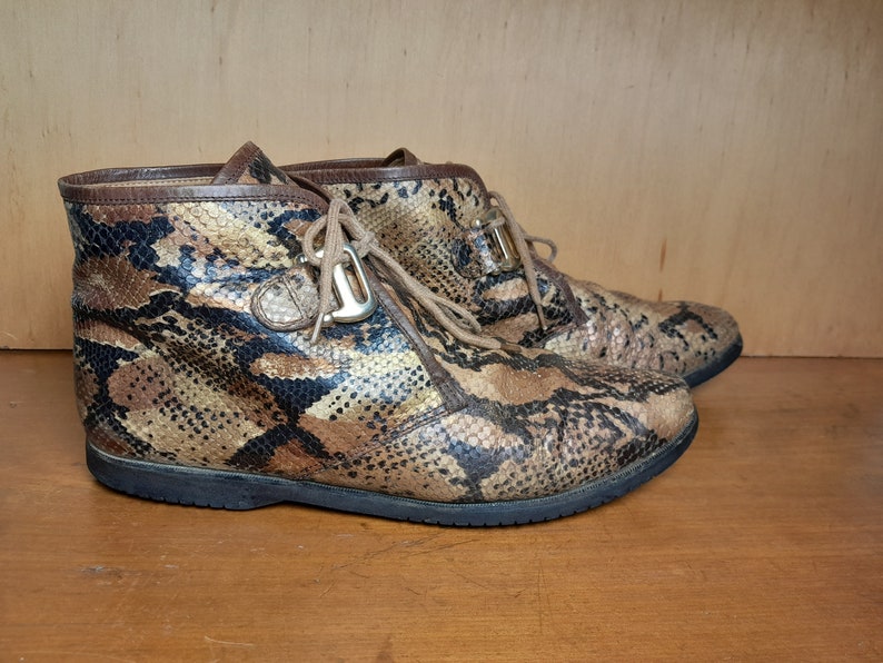 May include: A pair of brown and black snakeskin ankle boots with laces and a gold buckle.