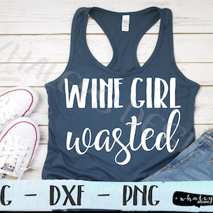 May include: A blue tank top with the text "Wine Girl Wasted" in white lettering. The tank top is laying on a white wooden surface with a pair of white sneakers and blue jeans.