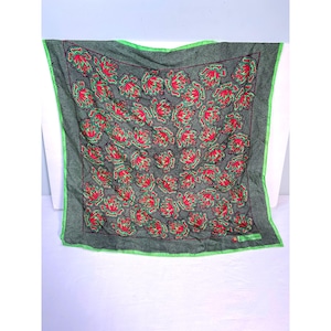 May include: Square scarf with a dark green background and a pattern of red and green floral designs. The scarf has a green border and a dotted pattern. The text "Le Nardone" is visible in the corner.