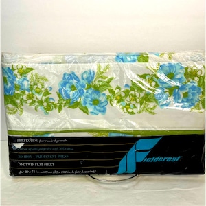 Puede incluir: Una sábana plana individual blanca con un estampado floral en tonos azules, verdes y amarillos. La sábana está empaquetada en plástico y lleva el nombre de la marca Fieldcrest. La sábana está hecha de una mezcla de 50% poliéster y 50% algodón y es de prensado permanente, lo que significa que no necesita planchado. La sábana está diseñada para un colchón de 39 x 75 pulgadas.