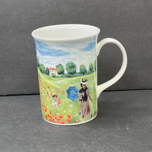 May include: White ceramic mug with a colorful painting of a woman and child walking through a field of red poppies. The painting is reminiscent of a famous Impressionist artwork.