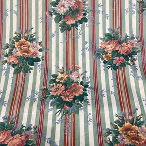 May include: A green and white striped fabric with a floral pattern. The flowers are pink, red, yellow, and white. The fabric has a vintage look.