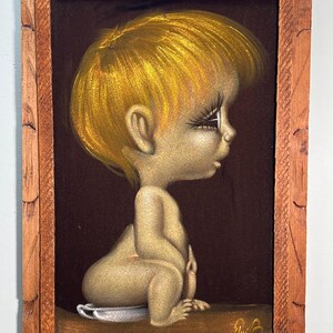 May include: A vintage painting of a seated child with golden hair and skin, framed in a rustic wooden frame. The child is depicted in a side profile against a dark brown background. The artwork has a unique, retro aesthetic.
