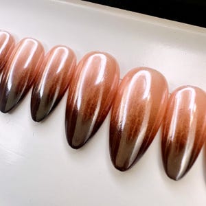 May include: Set of ten ombre press-on nails with a gradient from dark brown to light peach.