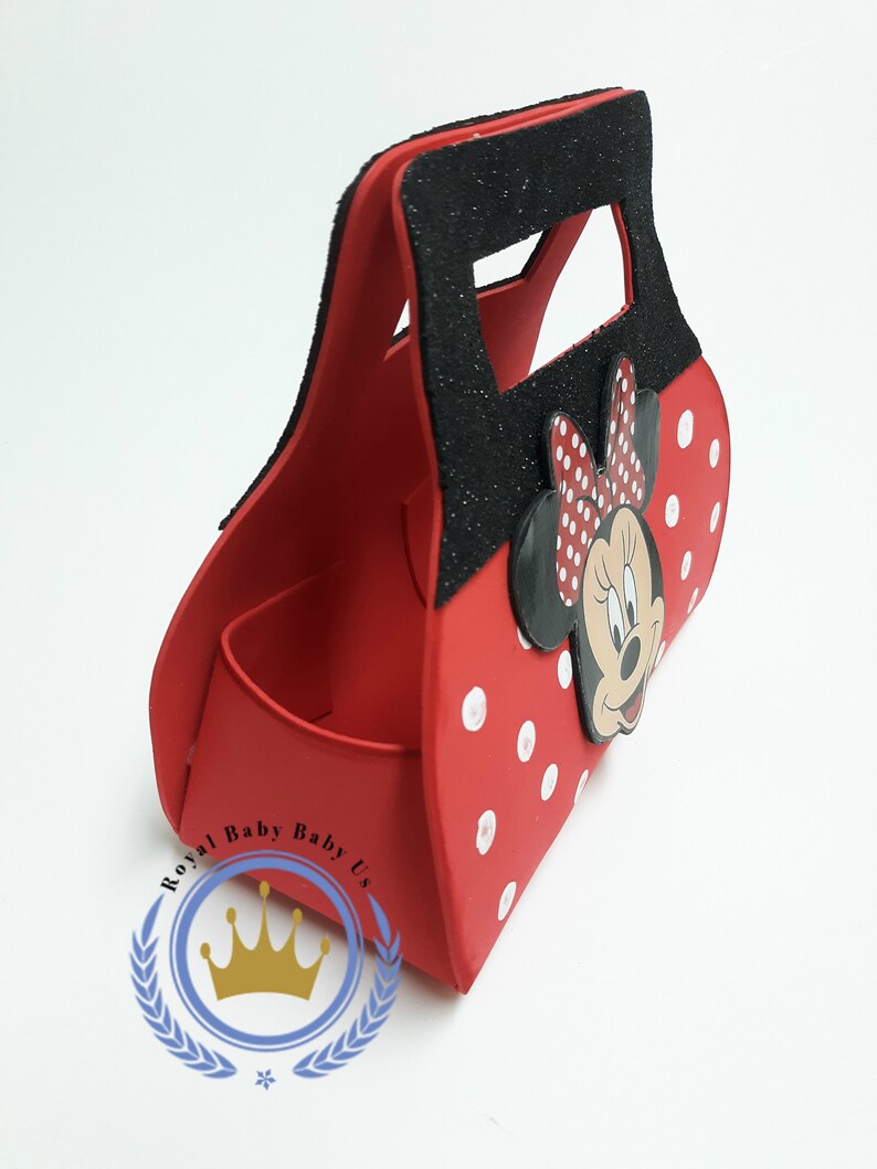 May include: Red Minnie Mouse-themed handbag with white polka dots and a black glitter handle. The bag features a Minnie Mouse face and bow. The bag has a compartment inside and is designed for carrying small items.