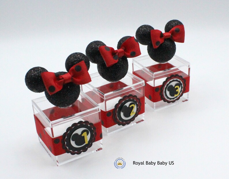 K&ouml;nnte beinhalten: Drei transparente Acrylboxen mit schwarzem und rotem Punktband. Jede Box hat einen schwarzen und roten Minnie Mouse Kopf mit einer roten Schleife oben. Die Boxen sind mit 1, 2 und 3 nummeriert.
